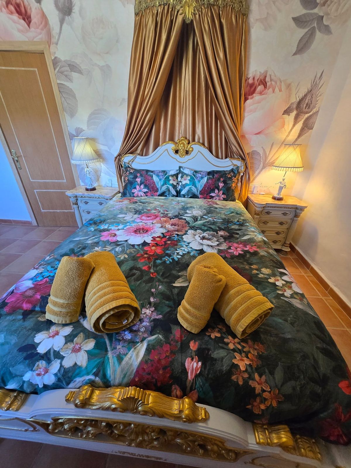 Bed with gold satin canopy and floral bedding