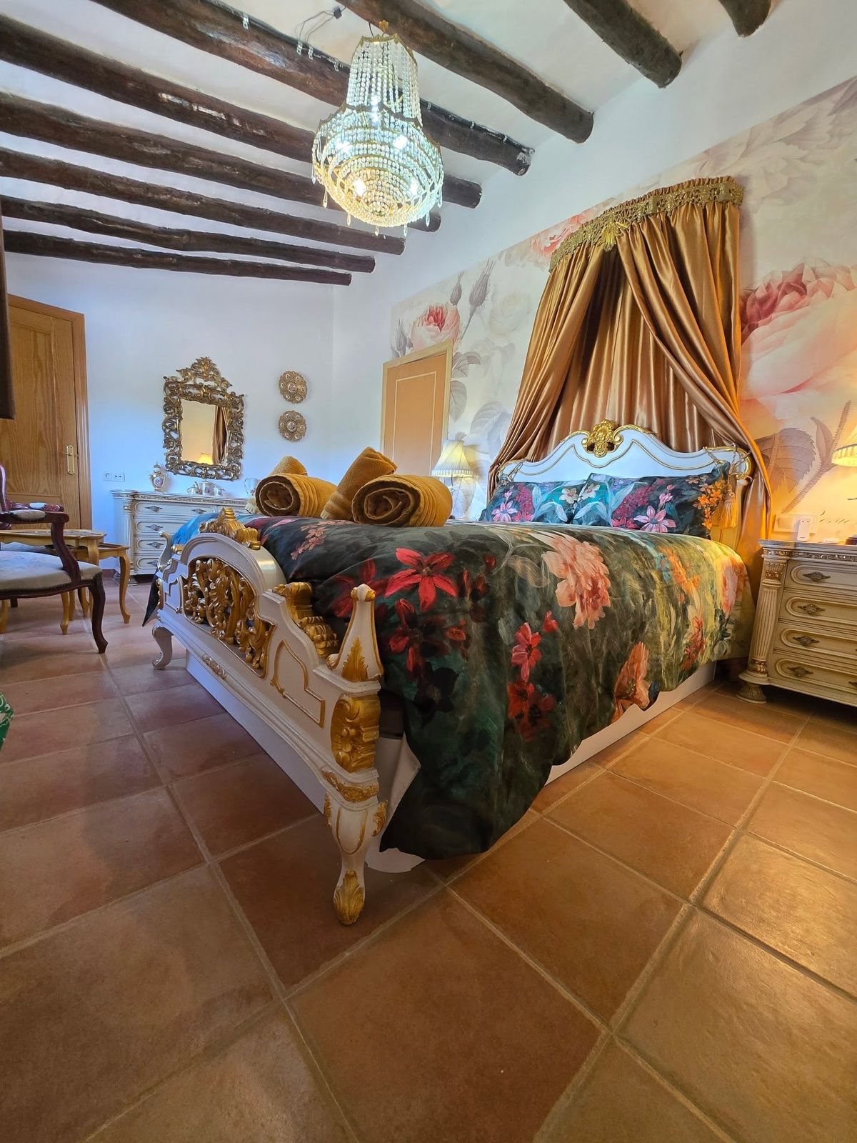 Bedroom with beamed ceiling, chandelier and rose mural